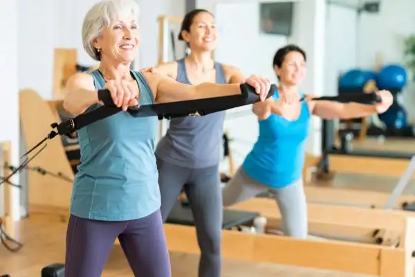 Toning Arms After 60: Empowering Womens Fitness Through Effective Weight Training 2 older woman doing weight training Ascot and resistance in the gym to tone upper arms